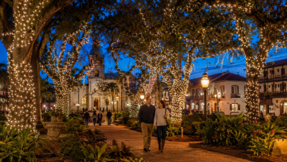 Couple walking beneath Christmas lights in St. Augustine’s Plaza de la Constitución near Cathedral Place